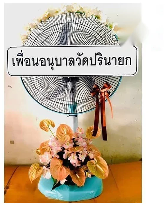 พัดลมผูกโบว์ริบบิ้นน้ำตาลแดง ช่อฐานหน้าวัวสีพีชแซมดอกชมพูอ่อน ขอบบนตะแกรงเรียงดอกขาวเล็ก