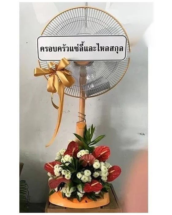 พัดลมเสาและฐานสีส้มผูกโบว์ทอง ช่อฐานหน้าวัวแดงล้อมเบญจมาศขาวดอกเล็ก มีใบเขียวตั้งเป็นยอด