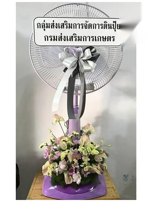 พัดลมสีม่วงอ่อนผูกโบว์ริบบิ้นเงินและเทาที่เสา ช่อฐานหน้าวัวชมพูอมเขียวและดอกเล็กสีเขียวมะนาว